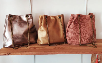 Cartera de cuero liso con cadena metálica en fondo de madera