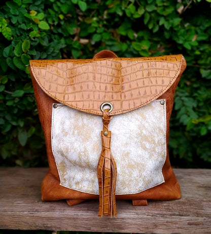 Mochila Amalia Marrón Tostado con textura croco y cierre metálico, fondo verde